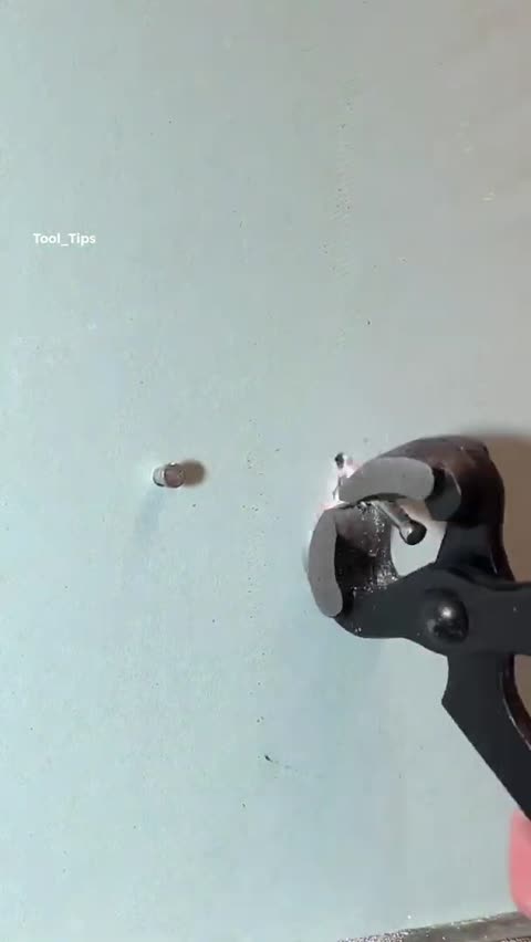 Two Metal Pins Driven Into a Light Gray Wall